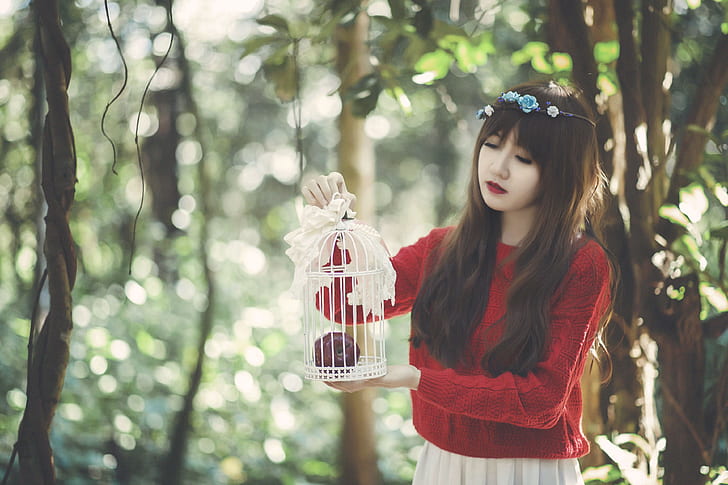 woman holding bird cage on forest