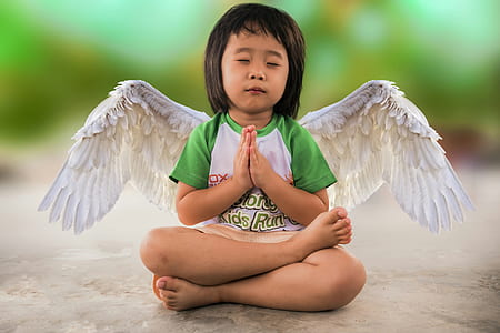 winged girl wearing white and green raglan crew-neck t-shirt praying