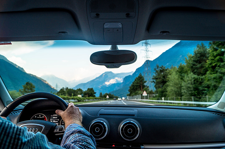 Man driving a car on road in the mountains of Switzerland