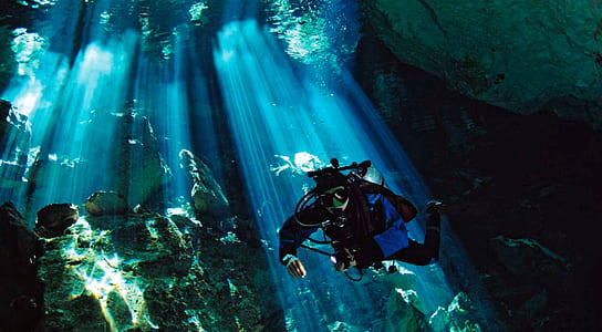 person diving underwater with sunlight