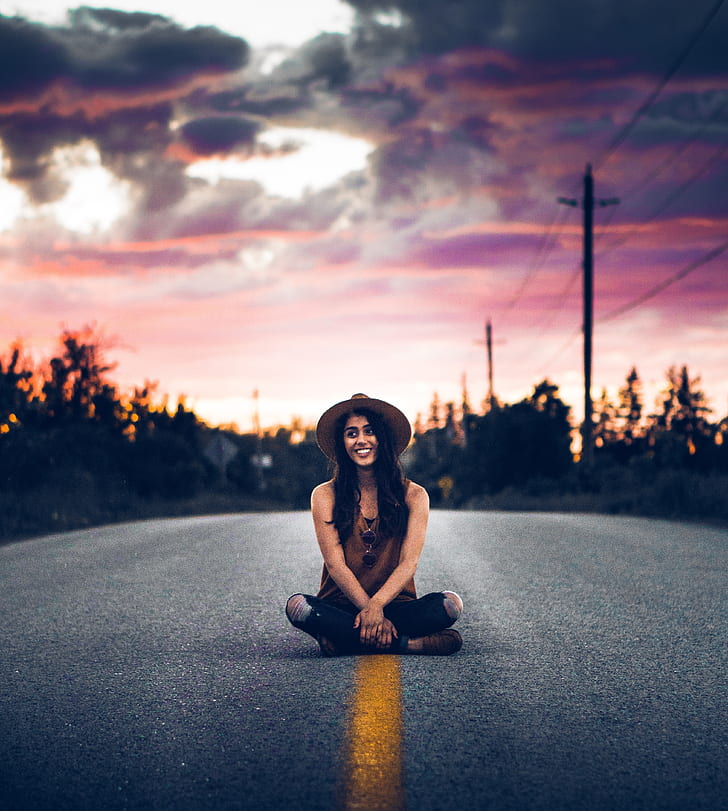 selective focus photography of woman sitting in the middle of the road