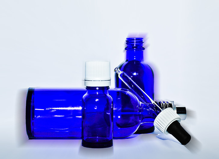 three blue glass bottles with dropper closeup photo