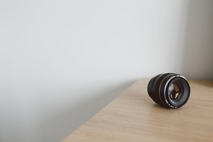 black DSLR camera lens on brown wooden surface