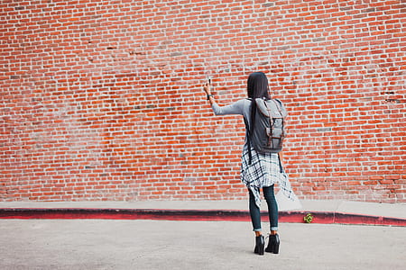 girl wearing gray shirt standing near brown brick wall at daytime