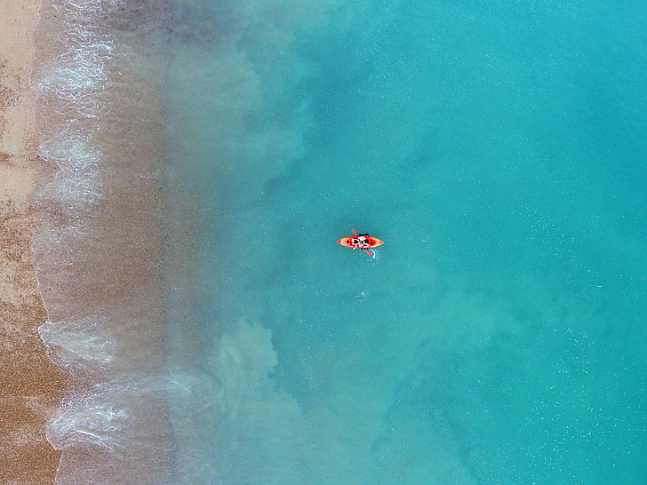 person riding kayak near brown sea shore