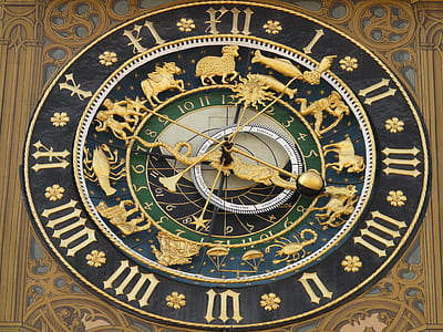 photo of black, brown, green, and blue clock with zodiac sign