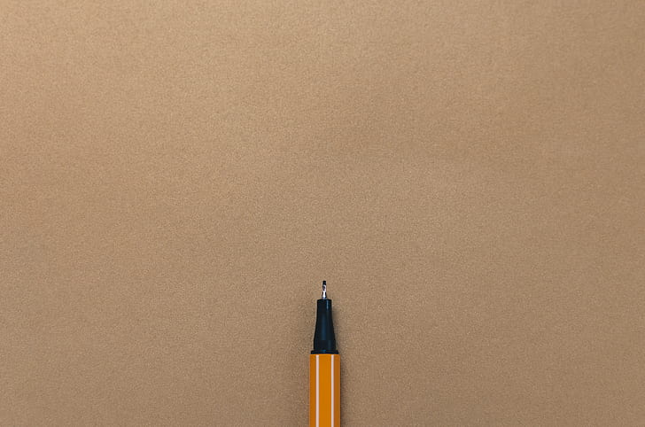 yellow ballpoint pen on beige surface