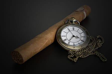 round brass-colored locket watch near brown tobacco