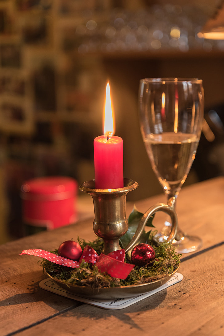 lighted red candle near champagne glass