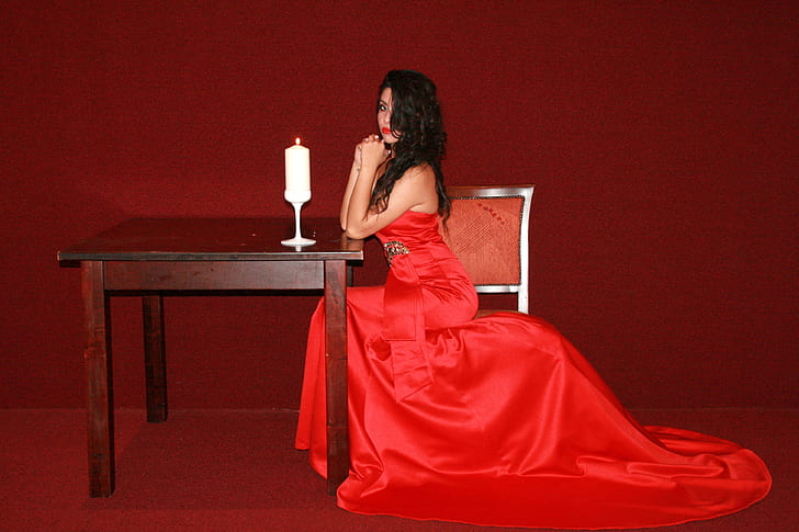 woman wearing red dress leaning on brown wooden table