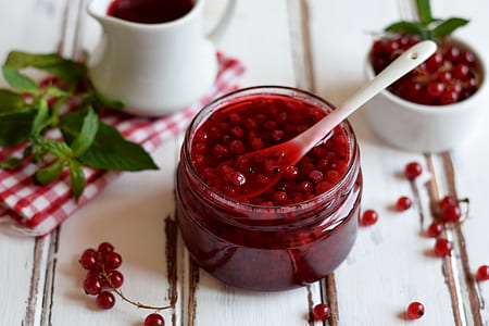 glass jar filled with red berry jam with spoon