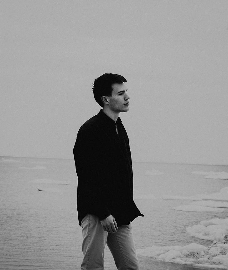 grayscale photography of man wearing dress shirt beside body of water
