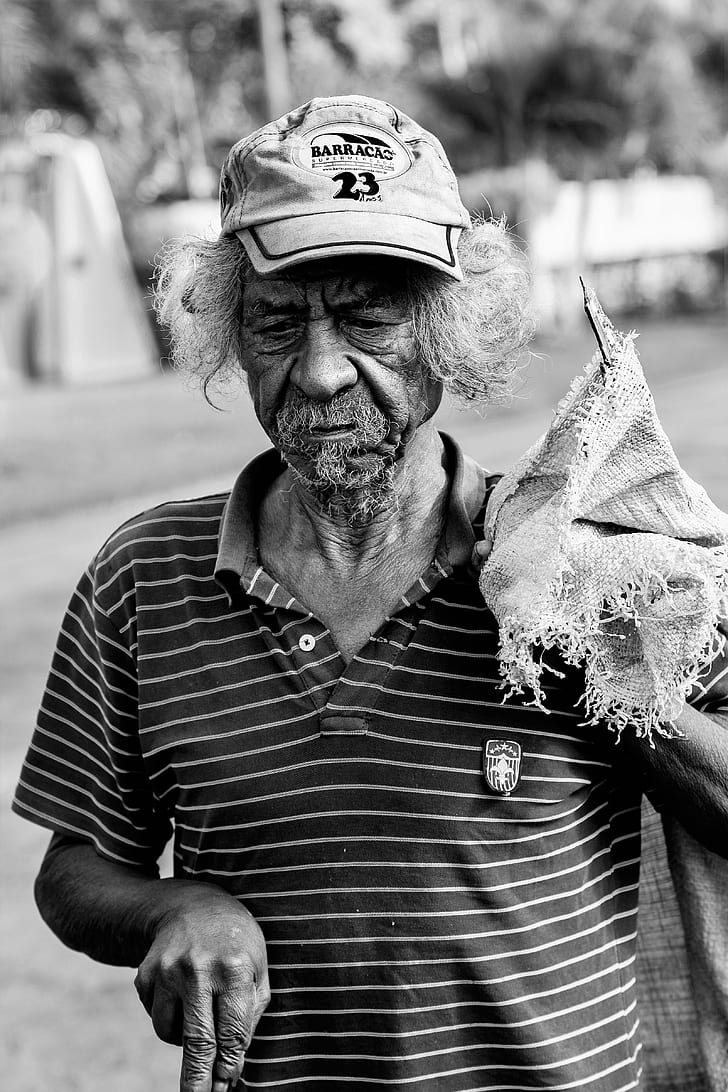Grayscale Photography Of Man Wearing Polo Shirt And Holding Sack