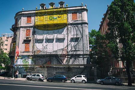 Wide-angle street shot of a building covered in street art. Image captured in Lisbon, Portugal