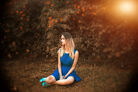 woman in blue sleeveless dress sitting on ground