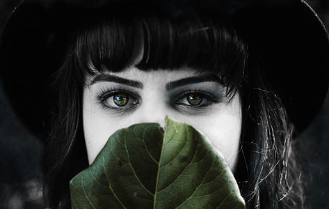selective color photography of woman behind green leaf