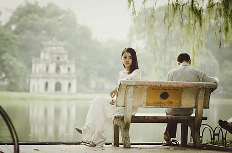 woman sitting on bench near bodies of water photograph