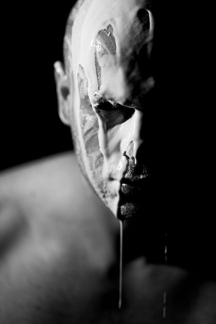 grayscale photo of man with white liquid on his face