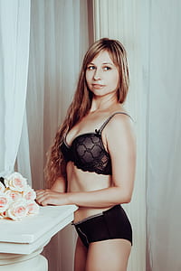 woman in black lace bra and pantie standing with hand near bouquet of flowers