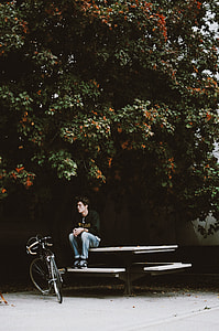 man sitting on bench facing bike