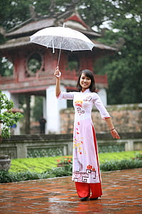woman in white, red, and orange traditional dress holding up umbrella