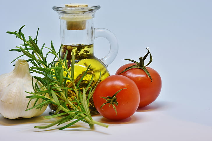two red tomatoes, olive oil jar and white onion