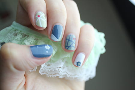 woman showing blue, white, and green nail manicure