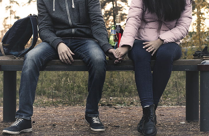 person holding their hand each other on bench
