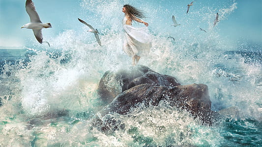 flock of gulls flying over woman on rock near body of water