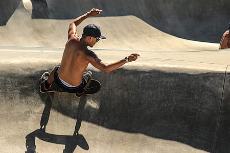 man wearing black shorts and cap riding skateboard