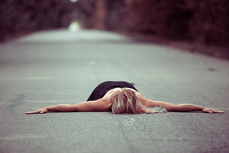 person lying in the middle on asphalt road