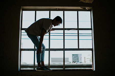 photography of man standing on window during daytime