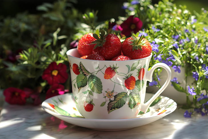 red strawberries on white ceramic teacup