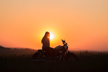 silhouette of woman riding motorcycle during sunset