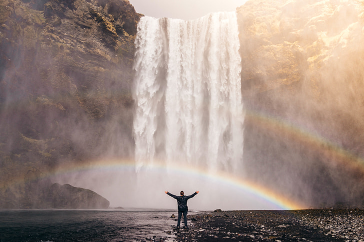 man in black long sleeve shirt in front of waterfalls