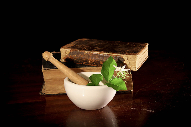 white and brown mortar and pestle beside two brown hardbound books