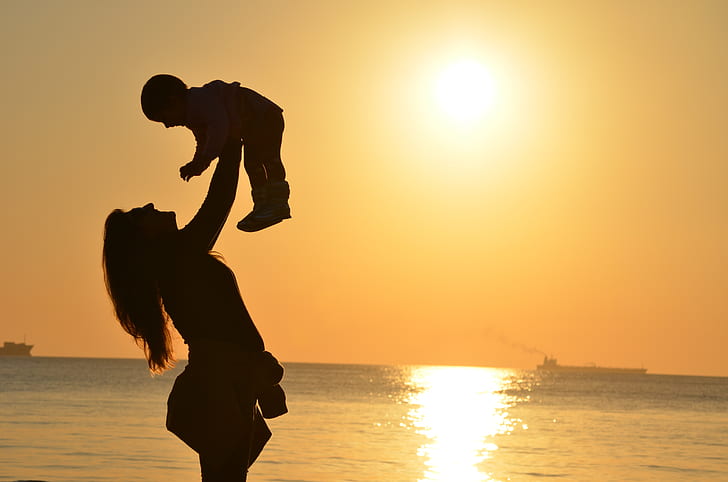 silhouette of woman carrying baby