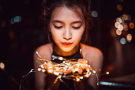 shallow focus photography of woman holding string lights