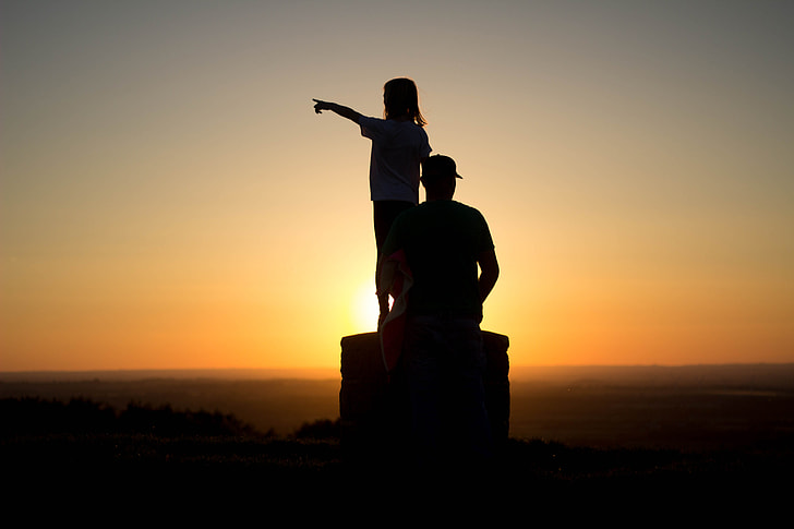 silhouette photo of man and girl during golden hour