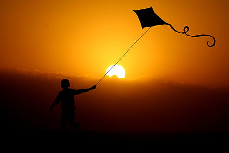 silhouette of child playing kite