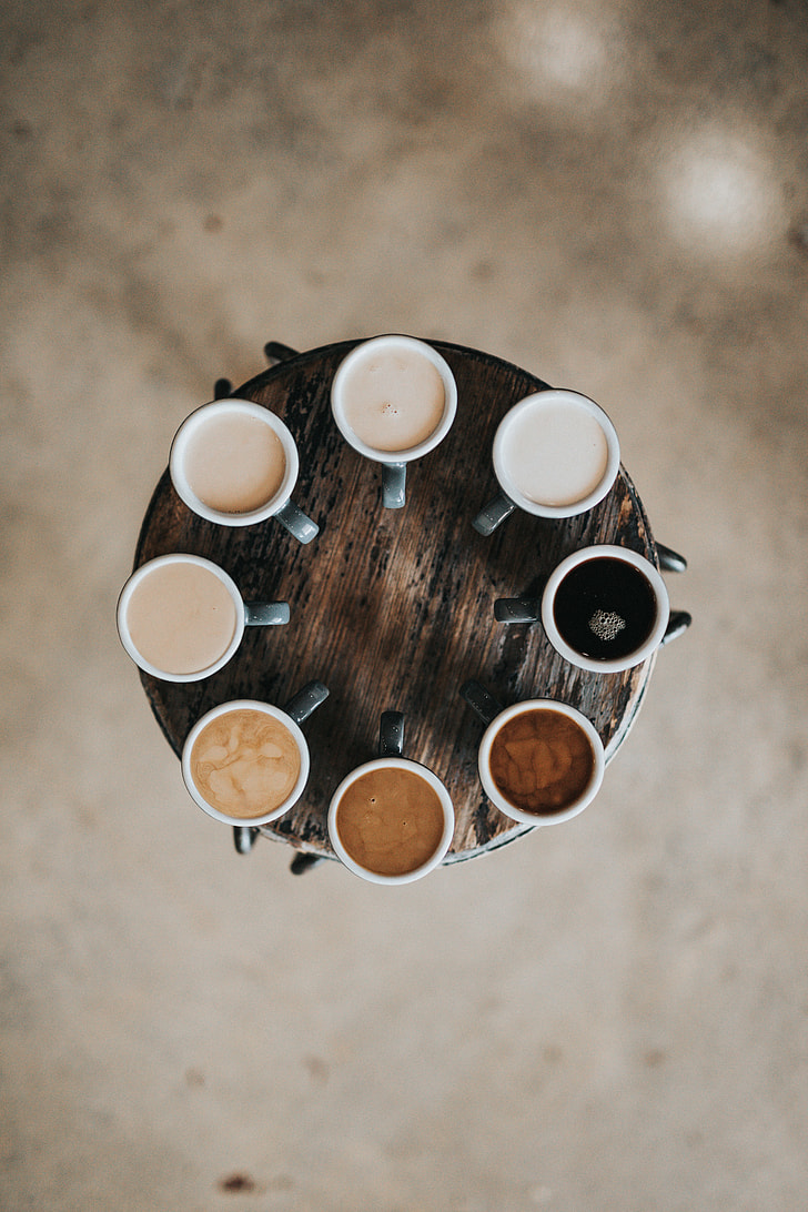 eight cups with coffee on brown wooden table