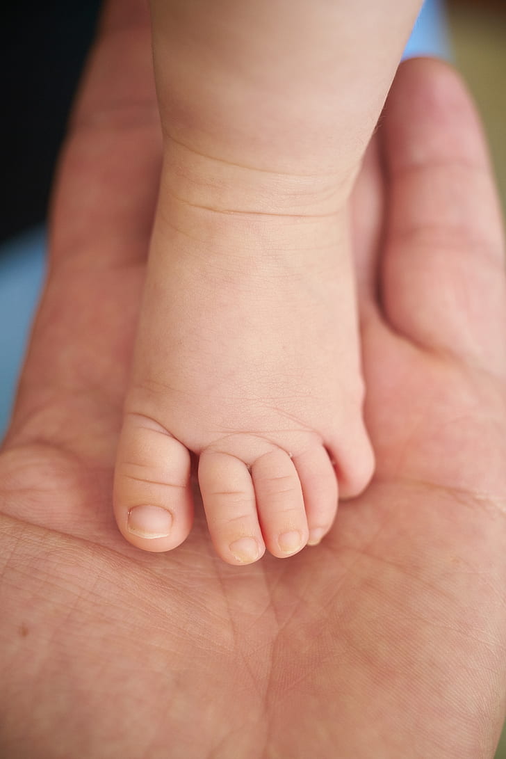baby left foot on person's left palm