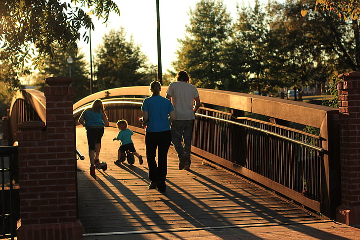 group of people on brown wooden bridge during sunset