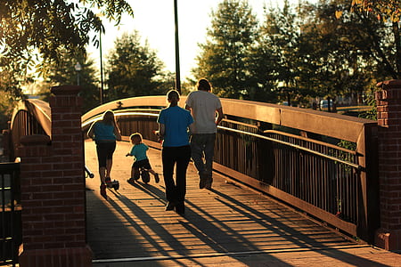group of people on brown wooden bridge during sunset