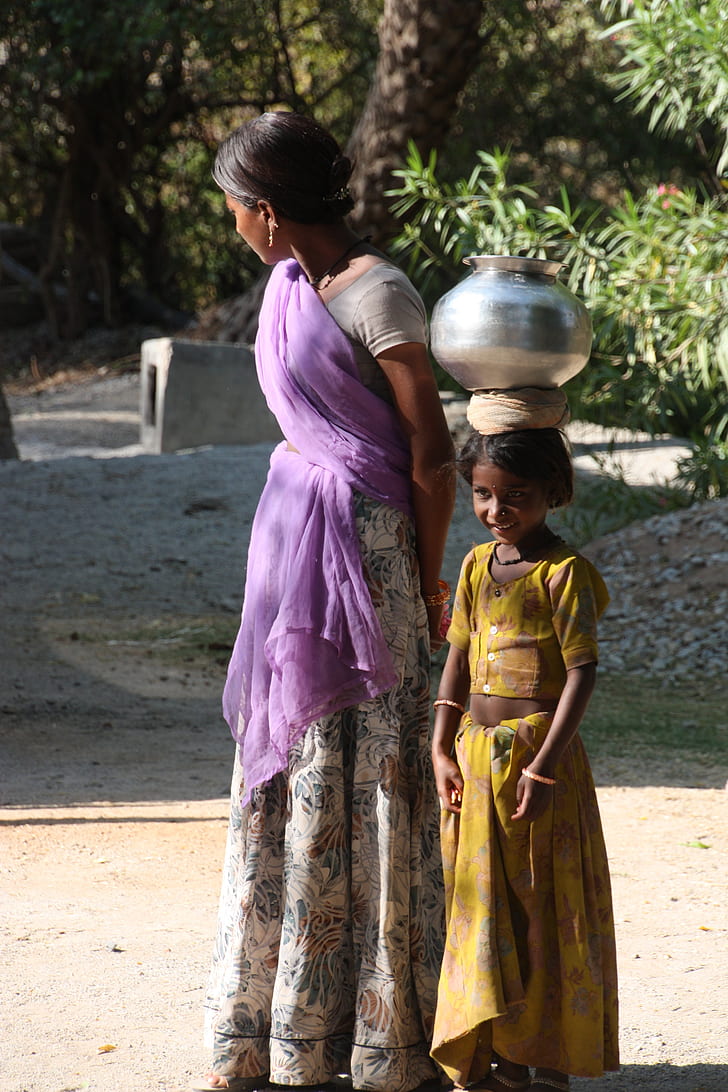 woman standing beside girl wearing sari dresses