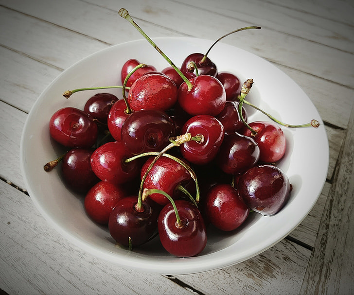 red cherries on white bowl