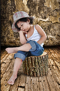 girl in white spaghetti strap shirt and blue denim jeans sits of brown tree log