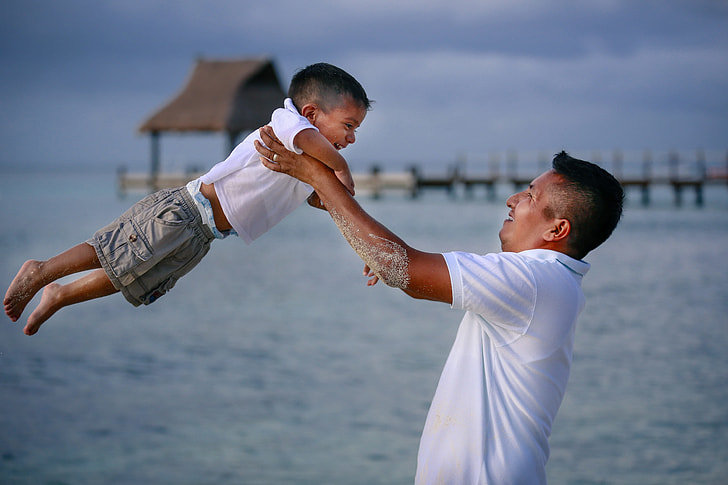 man carrying a boy in white polo shirt selective focus photography