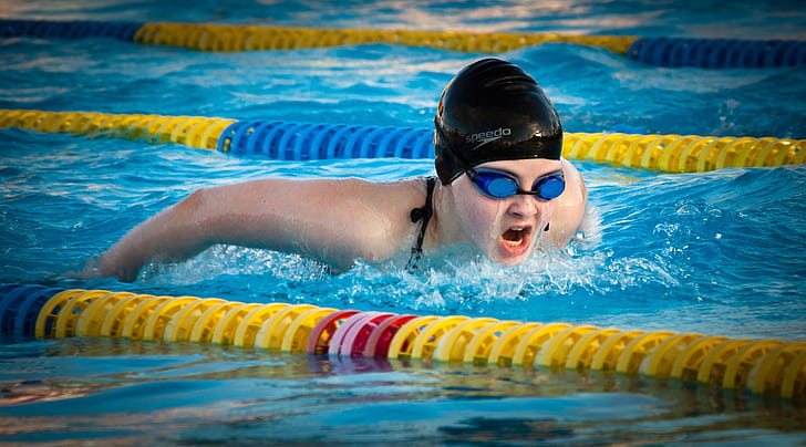person wearing black swim cap and blue goggles