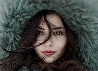 woman with black hair and green eyes wearing blue fur coat